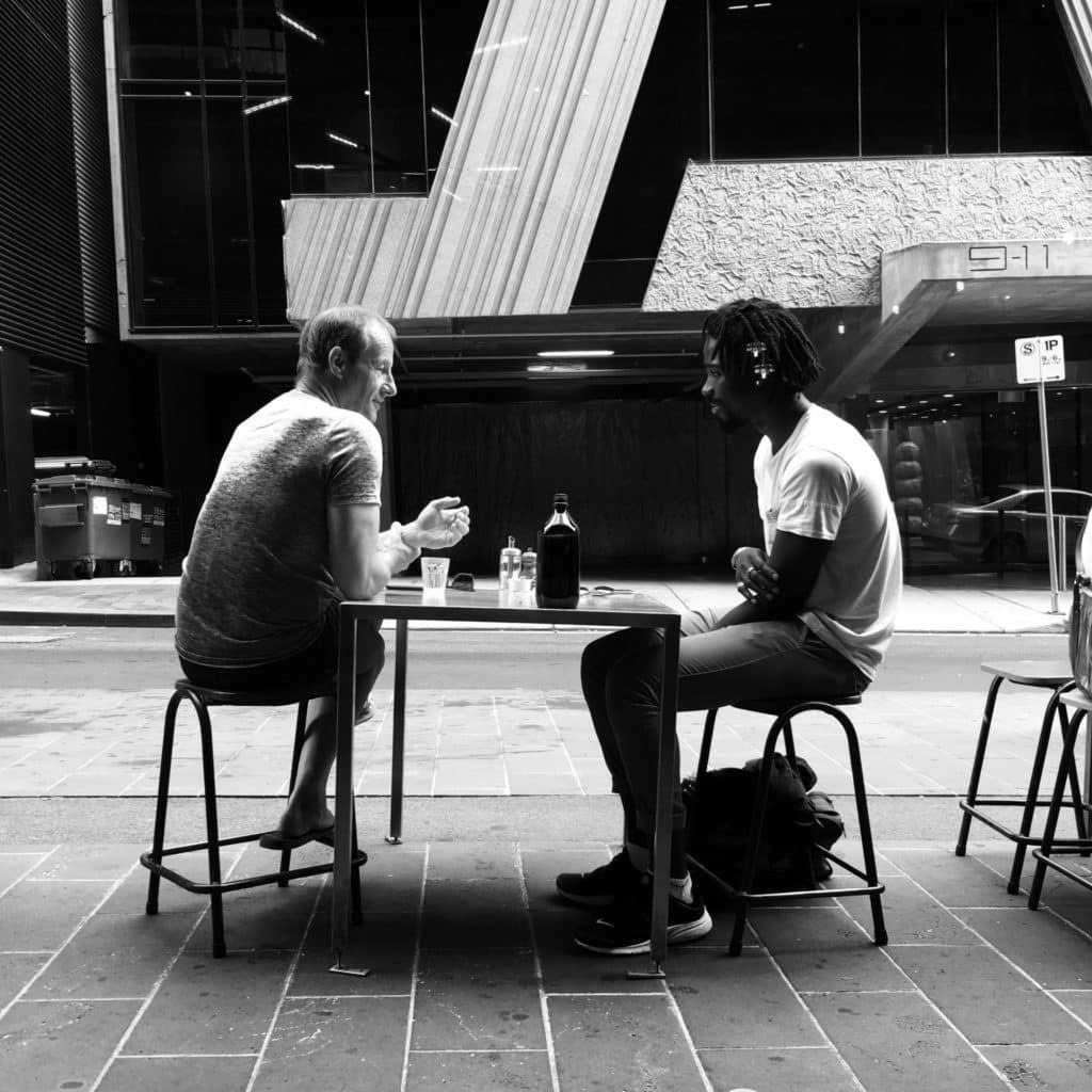 Photo of two men talking while sitting on chair
